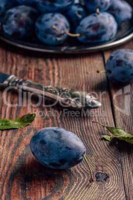 Ripe plums with leaves and knife