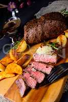 rustic medium butter beef steak with herbs and potato wedges