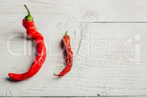 Two red chili peppers, on wooden background