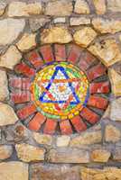 Mosaic star of David on stone wall.
