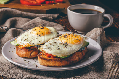 Italian toasts with vegetables and fried eggs on white plate and