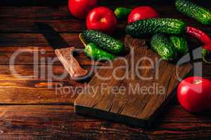 Cucumbers, tomatoes and chili peppers over wooden background.
