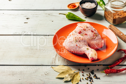 chicken leg quarter on plate with different spices