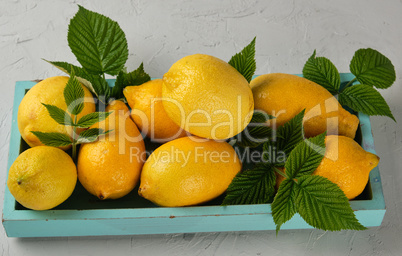 fresh ripe whole yellow lemons on a blue wooden board