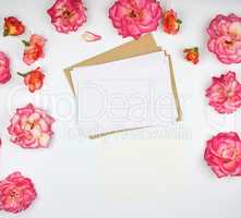 pink rose buds and a white paper envelope on a white background