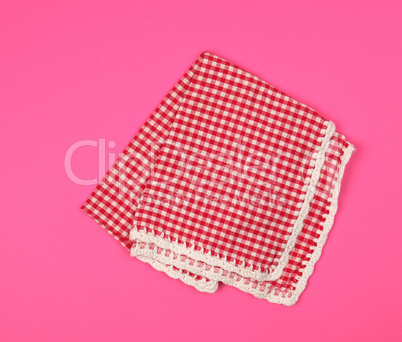 folded red kitchen towel in a cage on a pink background