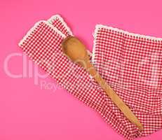 wooden spoon on a red kitchen towel, pink background