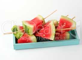 sliced ripe red watermelon with seeds on a wooden blue board