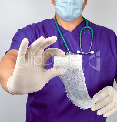 doctor in blue uniform and latex gloves holding white sterile ga
