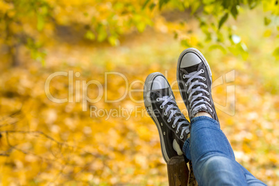 Teenage girl with sneakers is lying on bench closeup