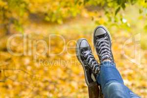 Teenage girl with sneakers is lying on bench closeup