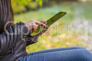 Teenage girl using digital tablet computer in autumn park