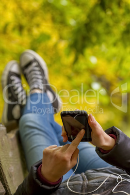 Teenage girl using smartphone in autumn park