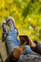 Teenage girl using smartphone in autumn park
