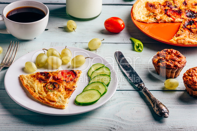 Slice of frittata with cup of coffee, grapes and muffins.