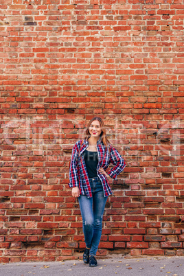 Portrait of young woman standing against brick wall