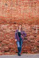 Portrait of young woman standing against brick wall
