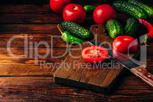 Sliced tomatoes on cutting board and cucumbers with chili pepper