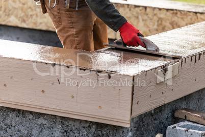 Construction Worker Using Wood Trowel On Wet Cement