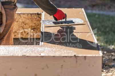 Construction Worker Using Trowel On Wet Cement Forming Coping