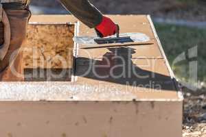 Construction Worker Using Trowel On Wet Cement Forming Coping