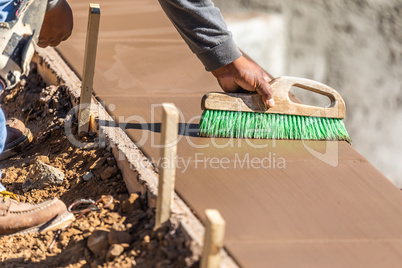 Construction Worker Using Brush On Wet Cement Forming Coping Aro