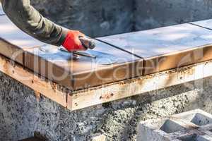 Construction Worker Using Trowel On Wet Cement Form Coping