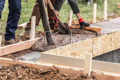 Construction Workers Pouring And Leveling Wet Cement Into Wood F