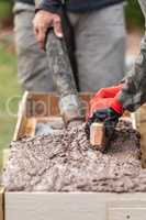 Construction Workers Pouring And Leveling Wet Cement Into Wood