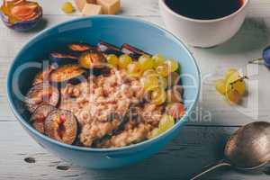 Porridge with fresh plum, green grapes and cup of coffee.