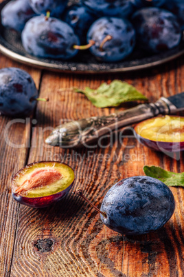 Ripe plums with leaves, water drops and knife