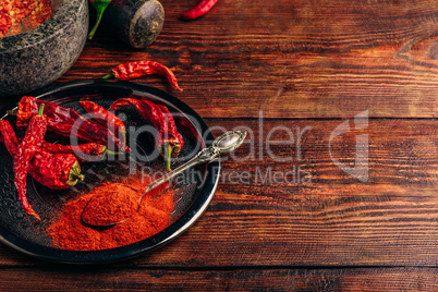 Ground and dried chili peppers on metal plate