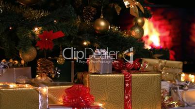 Woman placing gifts under Christmas tree near fireplace