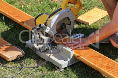 A worker saw wood with a chop saw