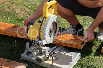 A worker saw wood with a chop saw