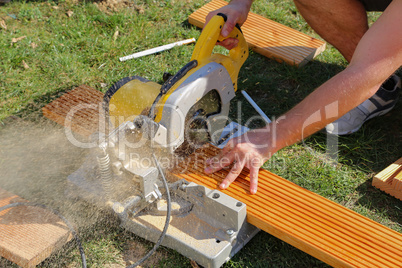 A worker saw wood with a chop saw