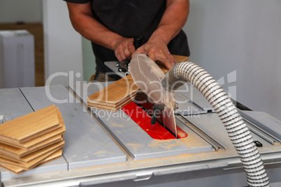 The worker cuts the parquet manually on a circular saw