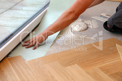 Worker laying parquet flooring. Worker installing wooden laminate flooring