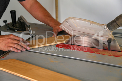 The worker cuts the parquet manually on a circular saw