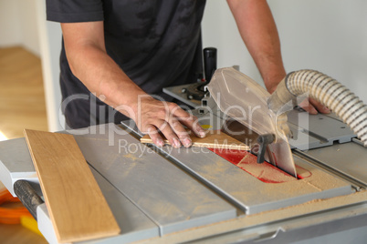 The worker cuts the parquet manually on a circular saw