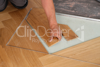 Worker laying parquet flooring. Worker installing wooden laminate flooring