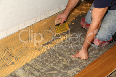 Worker laying parquet flooring. Worker installing wooden laminate flooring.