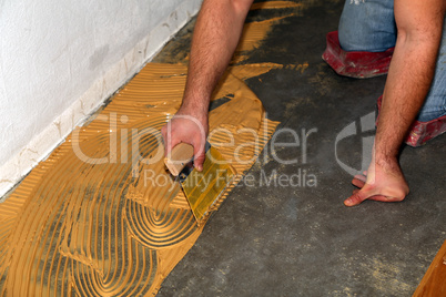 Worker laying parquet flooring. Worker installing wooden laminate flooring.