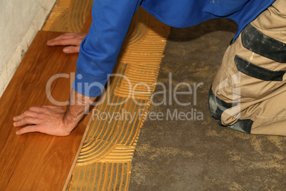 Worker laying parquet flooring. Worker installing wooden laminate flooring.