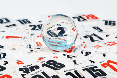 Glass ball on the sheets of the calendar scattered on the table