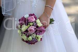 The bride holds a wedding bouquet in her hand