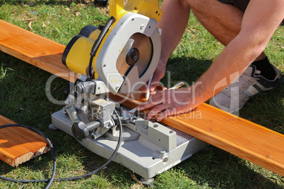 A worker saw wood with a chop saw