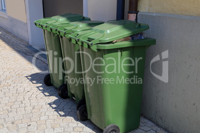 Green garbage cans are on the street