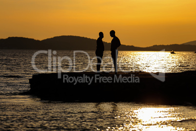 Silhouettes of men chatting on the beach at sunset