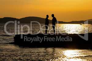 Silhouettes of men chatting on the beach at sunset